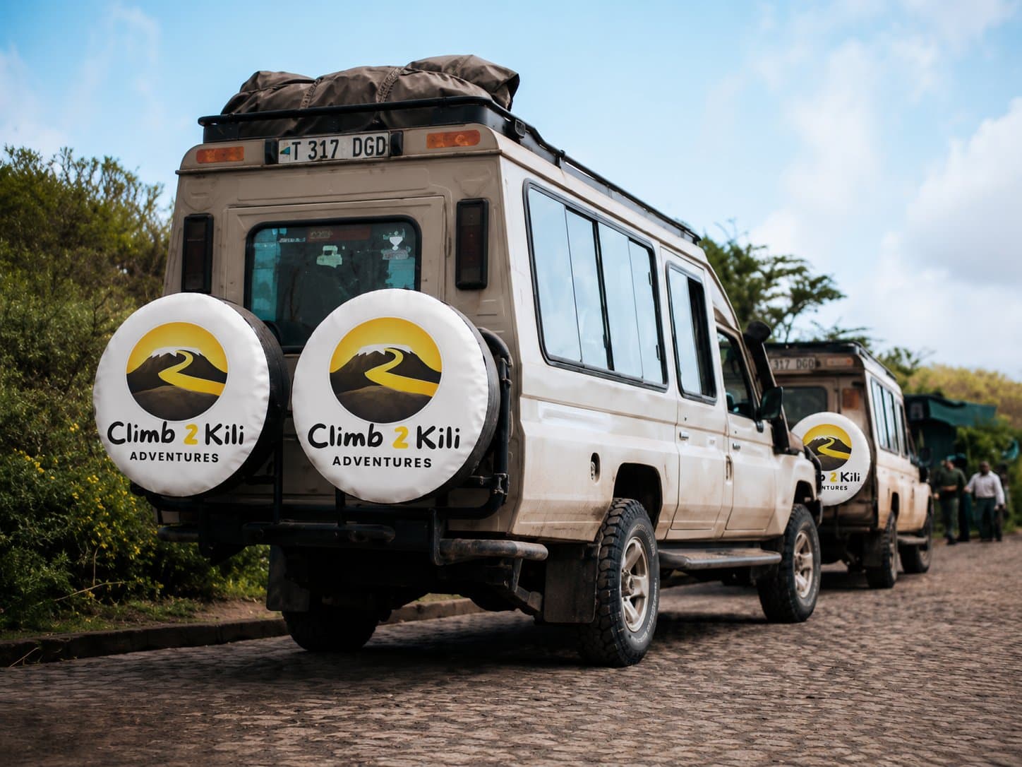 Fundador de pie con guías Kilimanjaro, porteros, chefs, conductores y miembros de la comunidad local bajo el Monte Kilimanjaro